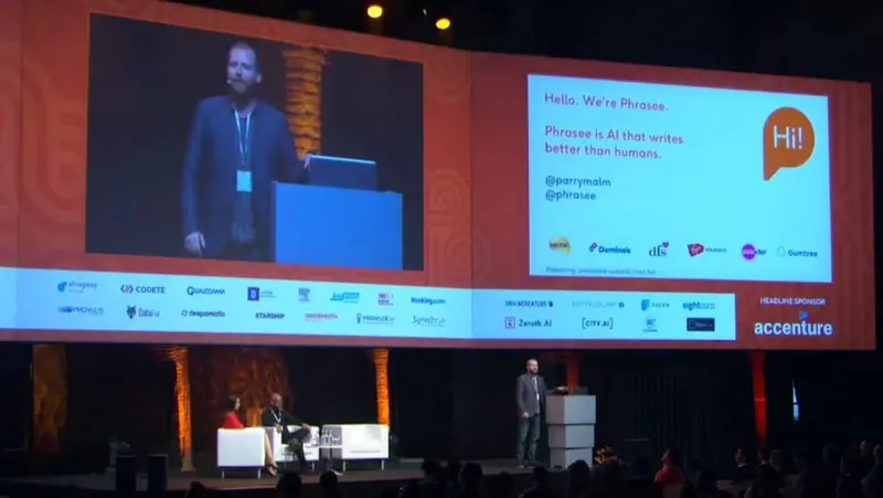 Parry Malm on stage at the AI World Summit in Amsterdam, beside a large presentation screen.